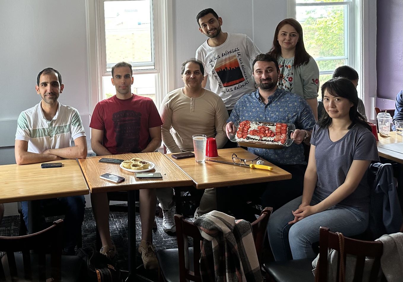 Milad and his graduate students posing with a cake